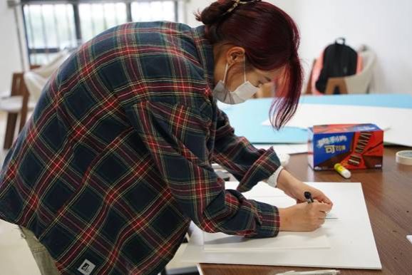A person writing on a piece of paperDescription automatically generated